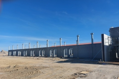 Fertiggestellte Stallanlage mit Reihe von Dachventilatoren und rotem Trapezblechdach