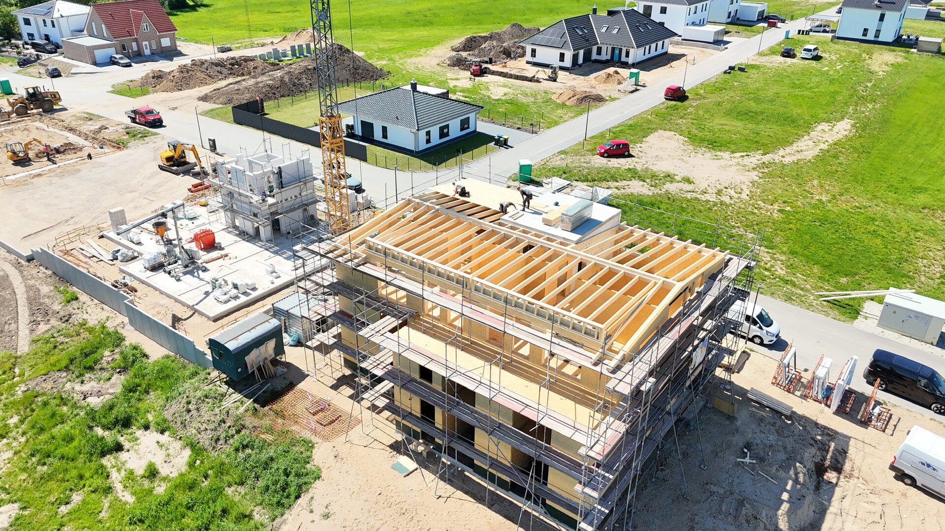 Luftaufnahme einer Baustelle mit Kran, Dachstuhl im Rohbau